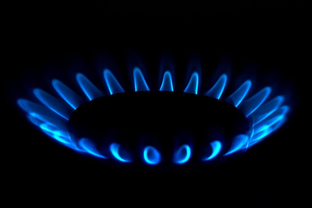 Gas burner ring alight with an even blue flame in a dark kitchen